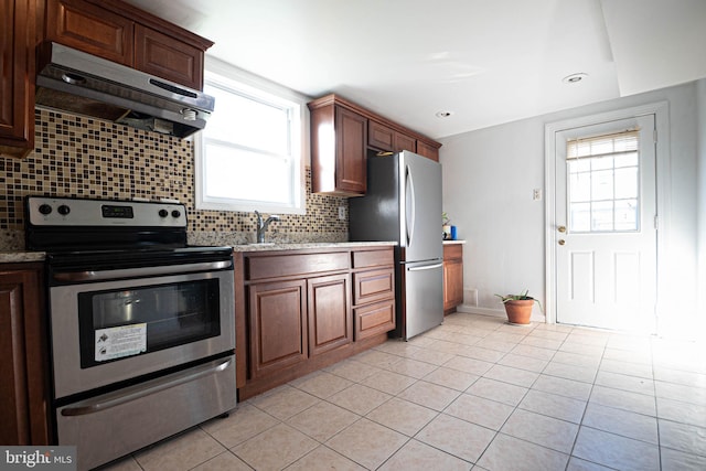 1262 Everett Ave, Woodbridge, VA 22191 - kitchen featuring appliances with stainless steel finishes, under cabinet range hood, light tile patterned floors, tasteful backsplash, and light stone countertops