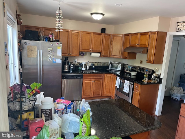 1020 Queens Ct, Herndon, VA 20170 - kitchen featuring stainless steel appliances, under cabinet range hood, brown cabinets, dark wood finished floors, and dark stone counters