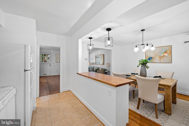 3718 Yolando Rd, Baltimore, MD 21218 - kitchen with butcher block countertops, freestanding refrigerator, a peninsula, pendant lighting, and light wood finished floors
