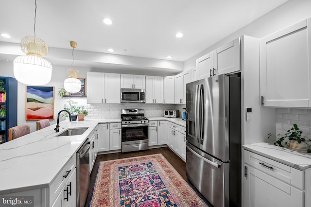 1309 Old Coldspring Ln W, Baltimore, MD 21211 - kitchen with appliances with stainless steel finishes, a peninsula, dark wood finished floors, tasteful backsplash, and white cabinetry