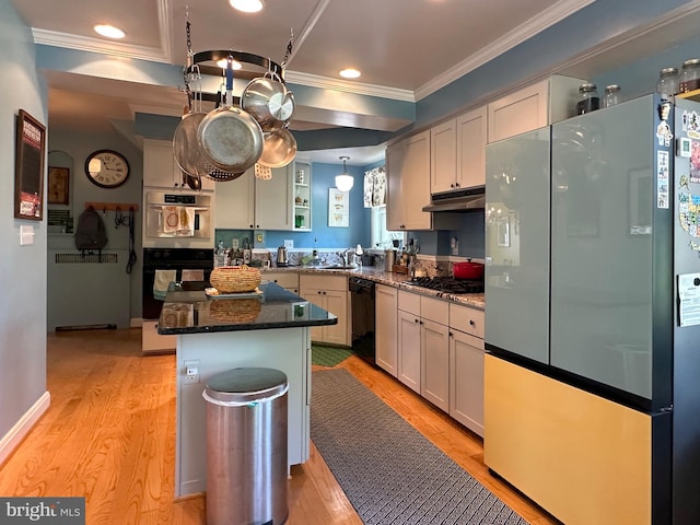 5512 Sefton Ave, Baltimore, MD 21214 - kitchen with black appliances, ornamental molding, light wood-style flooring, under cabinet range hood, and a kitchen island