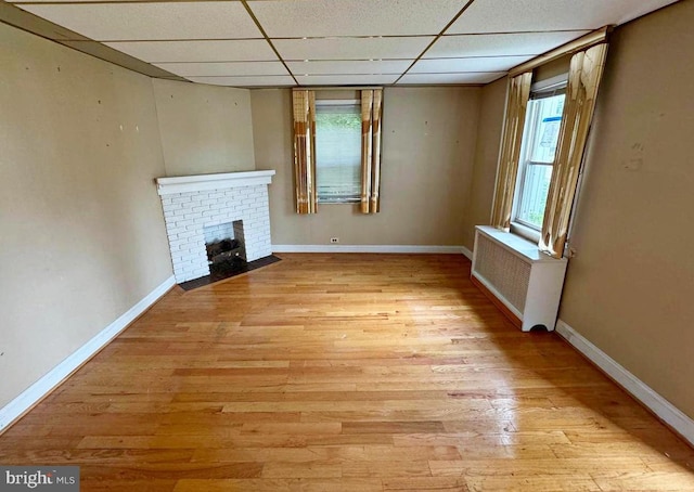 2805 Oakley Ave, Baltimore, MD 21215 - unfurnished living room with radiator, a paneled ceiling, light wood-style floors, and a fireplace