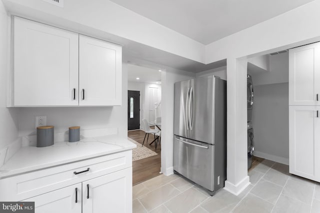 4621 A St SE, Washington, DC 20019 - kitchen with freestanding refrigerator, stacked washer / drying machine, white cabinets, and light stone countertops