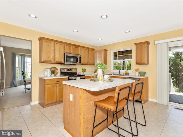 1402 Marian Way, Mount Airy, MD 21771 - kitchen featuring stainless steel appliances, light countertops, a center island, a kitchen bar, and light tile patterned floors