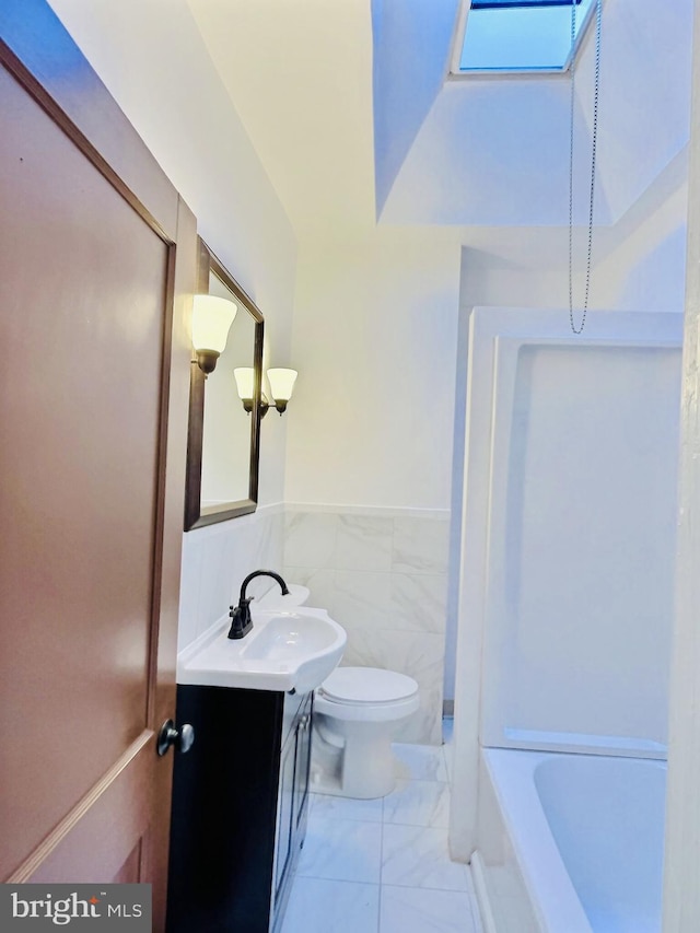 5945 Trinity St, Philadelphia, PA 19143 - bathroom with vanity, marble look tile flooring, wainscoting, and tile walls