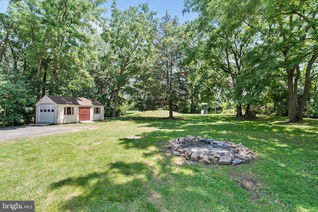 3409 Old York Rd, Furlong, PA 18925 - view of green lawn featuring an outdoor structure, a detached garage, a fire pit, and asphalt driveway