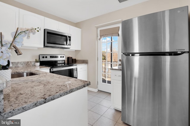 1409 E Abingdon Dr Unit 4, Alexandria, VA 22314 - kitchen with stainless steel appliances, light stone countertops, white cabinetry, and light tile patterned floors