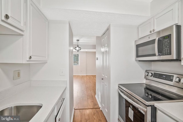 8549 Blue Rock Ln, Lorton, VA 22079 - kitchen with stainless steel appliances, light countertops, white cabinetry, and light wood-type flooring