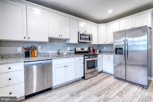 303 Lincoln Ave, Bristol, PA 19007 - kitchen featuring appliances with stainless steel finishes, light wood-style floors, white cabinetry, light stone countertops, and recessed lighting