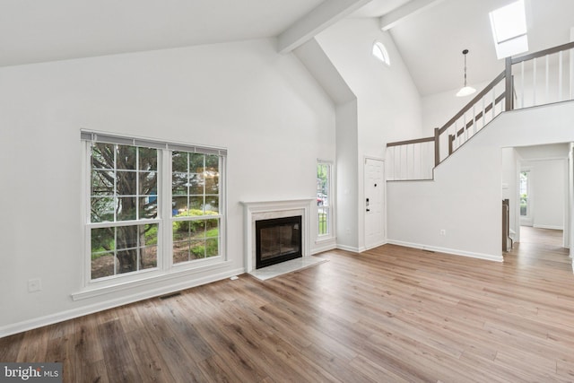 1544 Ingram Ter, Silver Spring, MD 20906 - unfurnished living room featuring a skylight, beamed ceiling, high vaulted ceiling, wood finished floors, and a high end fireplace