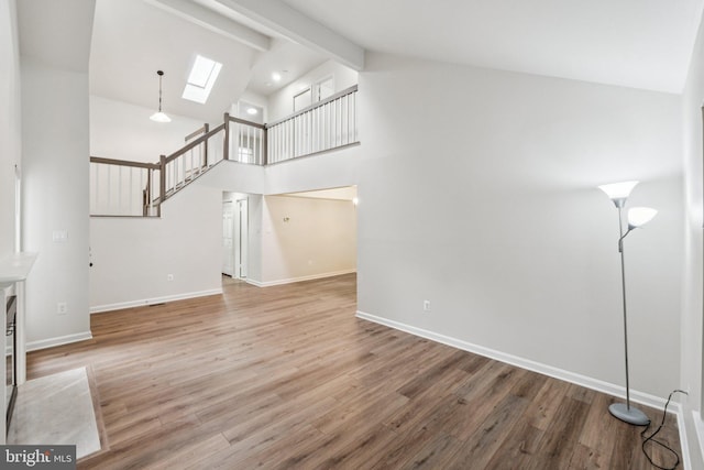 1544 Ingram Ter, Silver Spring, MD 20906 - unfurnished living room with a skylight, wood finished floors, beamed ceiling, high vaulted ceiling, and stairs