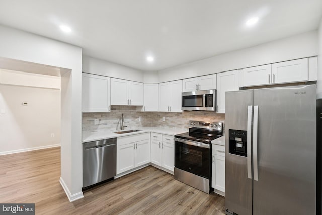 1544 Ingram Ter, Silver Spring, MD 20906 - kitchen with stainless steel appliances, light countertops, white cabinetry, decorative backsplash, and light wood-style floors