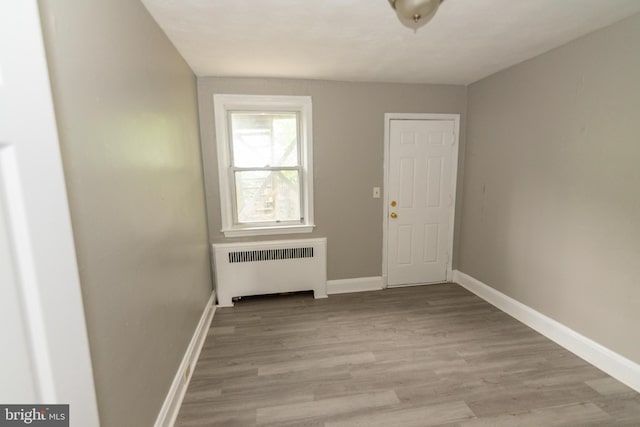 3116 Presstman St, Baltimore, MD 21216 - empty room with radiator heating unit and light wood-style flooring