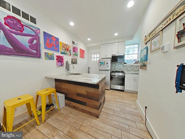 2230 N Mutter St, Philadelphia, PA 19133 - kitchen featuring stainless steel appliances, a peninsula, white cabinetry, backsplash, and recessed lighting