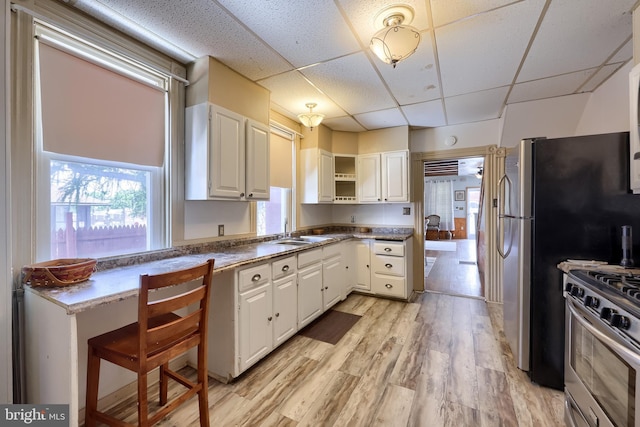 48 Ranck Ave, Lancaster, PA 17602 - kitchen featuring stainless steel gas range oven, a drop ceiling, open shelves, light wood-type flooring, and white cabinetry