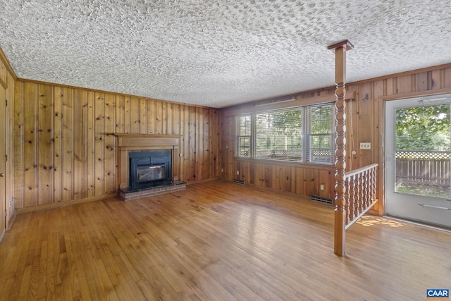 1562 Thomas Jefferson Pkwy, Charlottesville, VA 22901 - unfurnished living room featuring wood walls, wood finished floors, a glass covered fireplace, and a textured ceiling