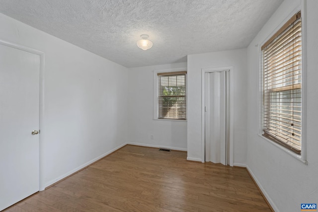 1562 Thomas Jefferson Pkwy, Charlottesville, VA 22901 - empty room with wood finished floors and a textured ceiling