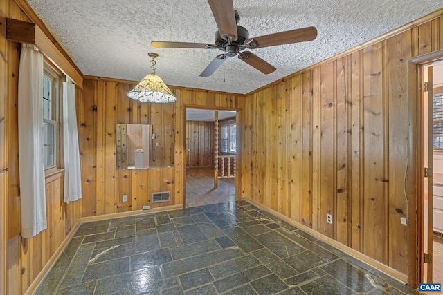 1562 Thomas Jefferson Pkwy, Charlottesville, VA 22901 - empty room with wood walls, stone finish flooring, ornamental molding, ceiling fan, and a textured ceiling
