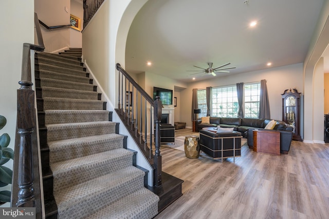 5745 Hawk Ridge Rd, Frederick, MD 21704 - living room with arched walkways, stairs, a ceiling fan, a fireplace, and wood finished floors