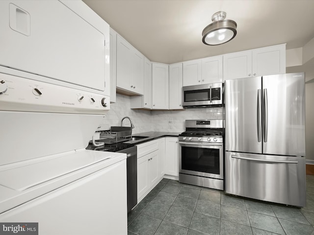 18615 Walkers Choice Rd # 2, Gaithersburg, MD 20886 - kitchen with appliances with stainless steel finishes, stacked washer / dryer, white cabinetry, tasteful backsplash, and dark tile patterned flooring