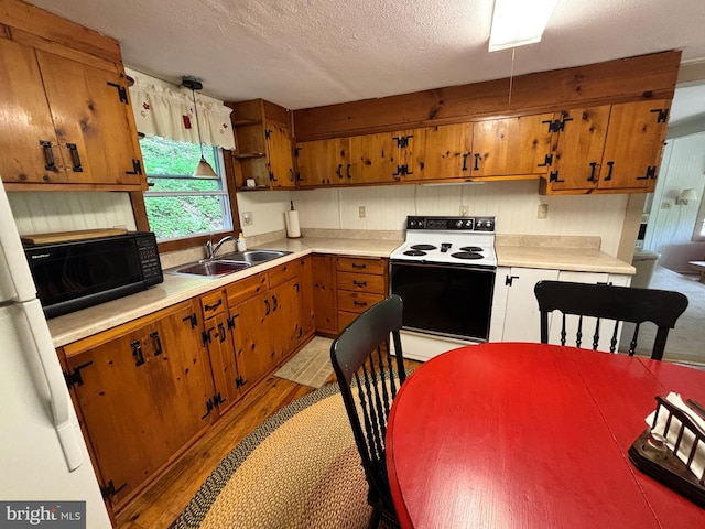 4677 Back Hollow Rd, Blain, PA 17006 - kitchen with white range with electric stovetop, black microwave, light wood-type flooring, brown cabinets, and a textured ceiling