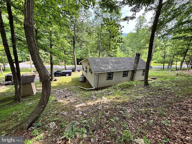 4677 Back Hollow Rd, Blain, PA 17006 - view of side of home with a chimney, a shingled roof, a wooded view, and an outbuilding