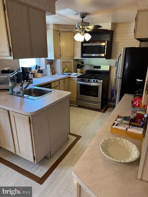 724 Susquehanna Rd, Philadelphia, PA 19111 - kitchen with stainless steel appliances, light countertops, a peninsula, a ceiling fan, and light wood-type flooring