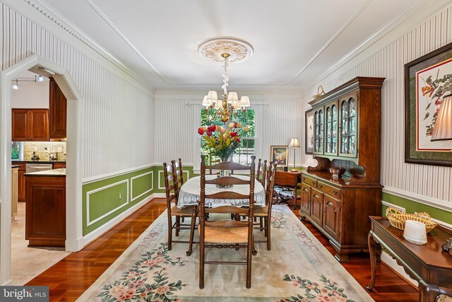 616 Silverstone Ct, Silver Spring, MD 20905 - dining area featuring wood finished floors, a chandelier, crown molding, a wainscoted wall, and wallpapered walls