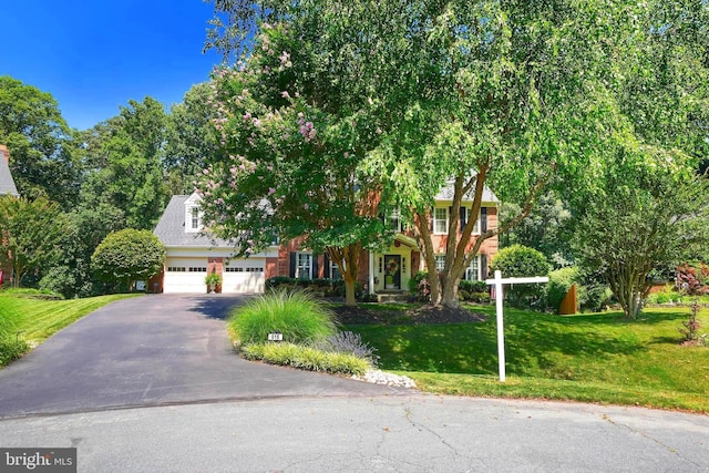 616 Silverstone Ct, Silver Spring, MD 20905 - view of property hidden behind natural elements with asphalt driveway, a front lawn, and a garage