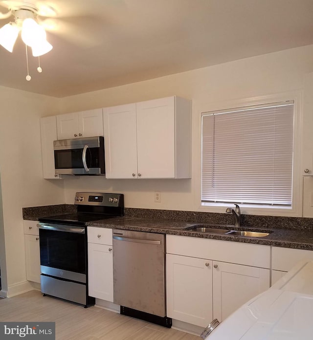 244 6th St, Colonial Beach, VA 22443 - kitchen featuring appliances with stainless steel finishes, white cabinetry, light wood finished floors, a ceiling fan, and dark stone counters