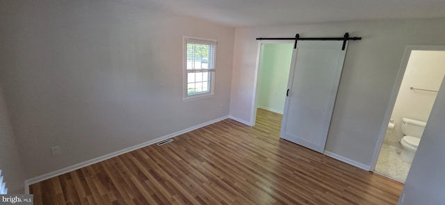 3478 Pence Ct, Annandale, VA 22003 - unfurnished bedroom with a barn door, wood finished floors, and connected bathroom