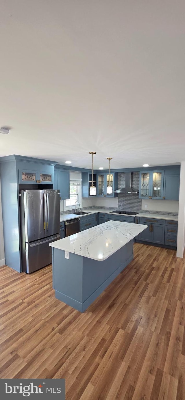 3478 Pence Ct, Annandale, VA 22003 - kitchen featuring appliances with stainless steel finishes, a center island, wall chimney range hood, light wood-type flooring, and glass insert cabinets