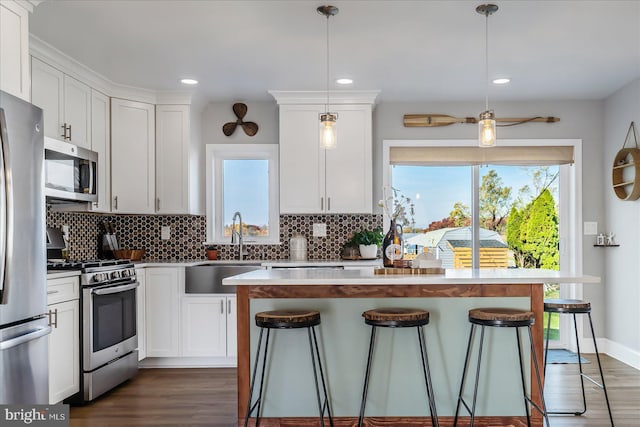 6934 River Drive Rd, Sparrows Point, MD 21219 - kitchen featuring stainless steel appliances, a kitchen bar, decorative backsplash, dark wood-style floors, and white cabinets