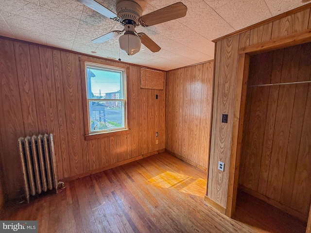 507 Market St, New Cumberland, PA 17070 - unfurnished bedroom featuring radiator, light wood-style floors, wooden walls, and a ceiling fan