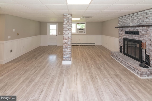640 Bollinger Rd, Littlestown, PA 17340 - unfurnished living room with a wainscoted wall, a paneled ceiling, a baseboard radiator, a brick fireplace, and decorative columns