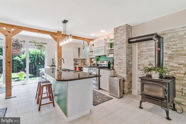 2090 Clearview Dr, Owings, MD 20736 - kitchen with white appliances, a wood stove, dark countertops, white cabinetry, and hanging light fixtures