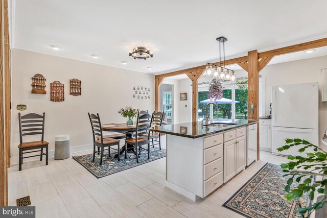 2090 Clearview Dr, Owings, MD 20736 - kitchen with white appliances, dark countertops, an island with sink, white cabinetry, and hanging light fixtures