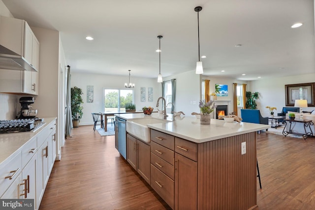 11100 Slate Landing Ln, Nokesville, VA 20181 - kitchen featuring appliances with stainless steel finishes, wall chimney range hood, recessed lighting, open floor plan, and a warm lit fireplace