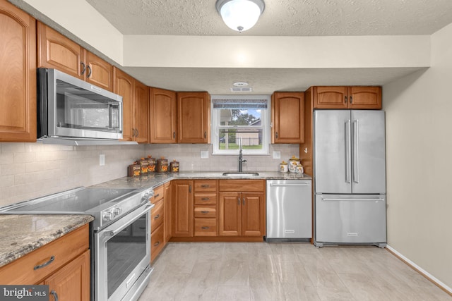 1848 Statesman Ct, Severn, MD 21144 - kitchen with stainless steel appliances, a textured ceiling, decorative backsplash, light stone countertops, and brown cabinetry