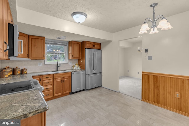 1848 Statesman Ct, Severn, MD 21144 - kitchen featuring stainless steel appliances, brown cabinetry, a textured ceiling, backsplash, and a chandelier