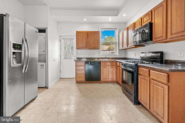 3915 Falls Rd, Baltimore, MD 21211 - kitchen featuring black appliances, stacked washer and clothes dryer, recessed lighting, dark countertops, and brown cabinetry