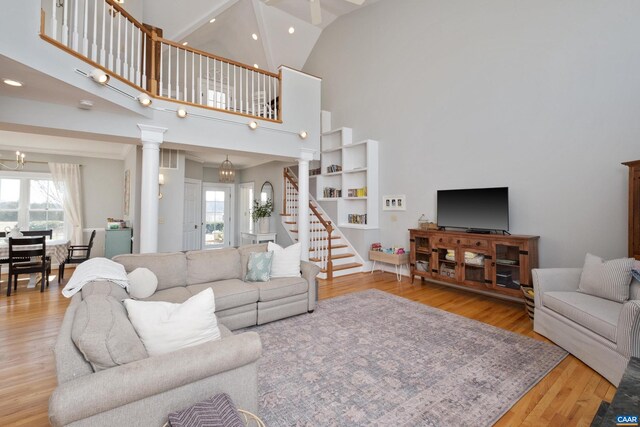 928 Slate Mill Rd Unit B, Stanardsville, VA 22973 - living room featuring wood finished floors, decorative columns, stairway, high vaulted ceiling, and a chandelier