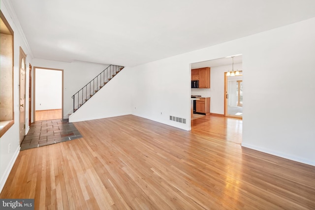 2621 Dartmouth Woods Rd, Wilmington, DE 19810 - unfurnished living room with light wood-style flooring, stairs, and a chandelier