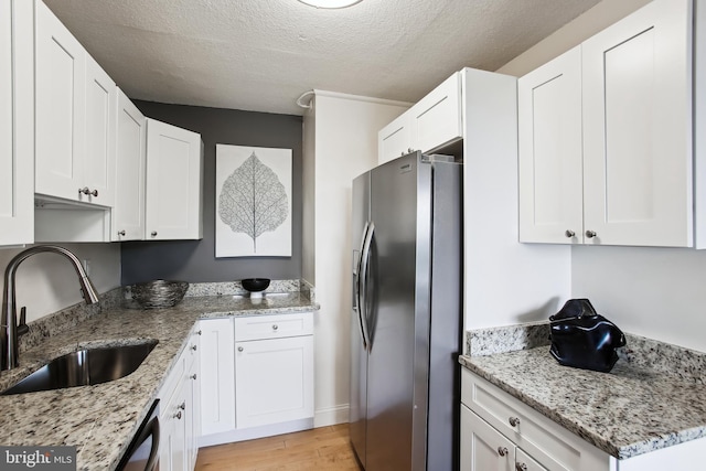 2059 Huntington Ave Unit 1406, Alexandria, VA 22303 - kitchen with appliances with stainless steel finishes, light wood finished floors, white cabinets, light stone counters, and a textured ceiling