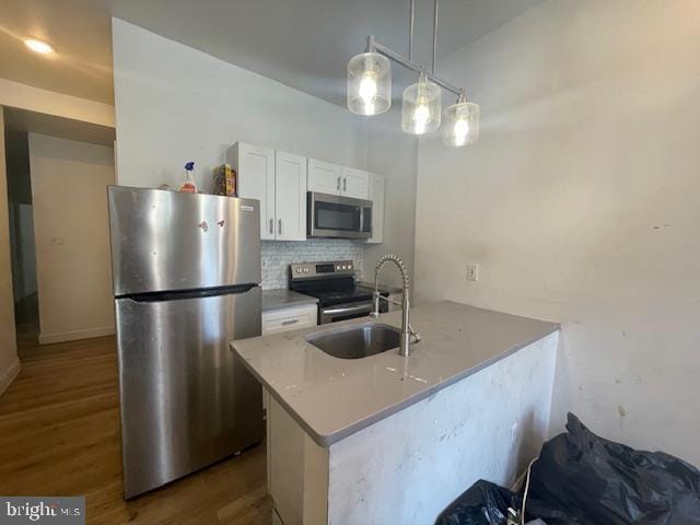 2521 N 12th St, Philadelphia, PA 19133 - kitchen featuring stainless steel appliances, white cabinets, dark wood-style flooring, tasteful backsplash, and a peninsula
