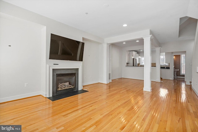 19 Yogurt Ln, Baltimore, MD 21231 - unfurnished living room with decorative columns, light wood-type flooring, a fireplace with flush hearth, and recessed lighting