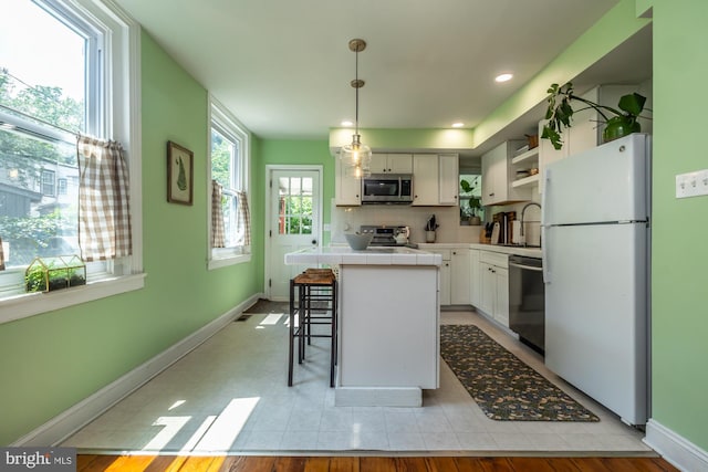 239 W Barnard St, West Chester, PA 19382 - kitchen featuring appliances with stainless steel finishes, tile countertops, a center island, white cabinets, and open shelves