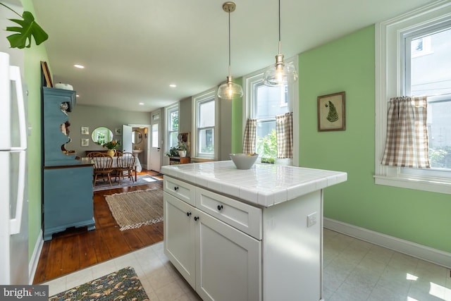 239 W Barnard St, West Chester, PA 19382 - kitchen featuring tile counters, white cabinets, freestanding refrigerator, light tile patterned floors, and pendant lighting