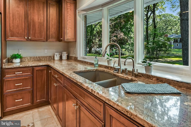 10 Sonora Dr, Pasadena, MD 21122 - kitchen featuring light stone counters, brown cabinets, and light tile patterned floors