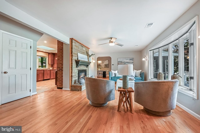 10 Sonora Dr, Pasadena, MD 21122 - living room with ceiling fan, light wood-style flooring, a stone fireplace, and arched walkways